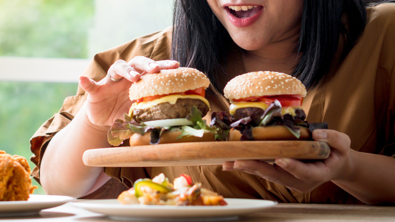 binge eating woman with two burgers