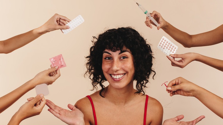 a woman sits smiling as hands hold up different birth control options