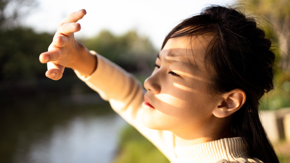 A child shielding her face from the sun 