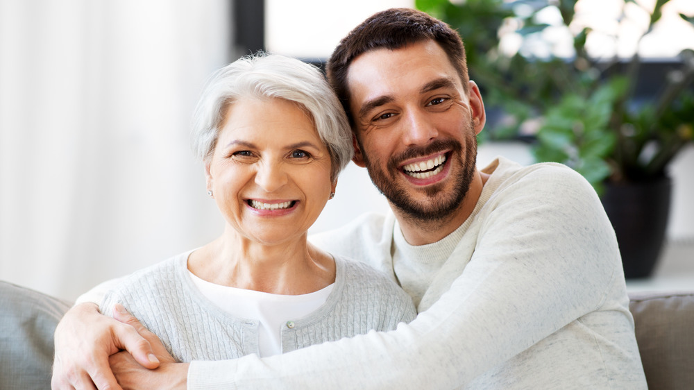 man sitting next to woman hugging her