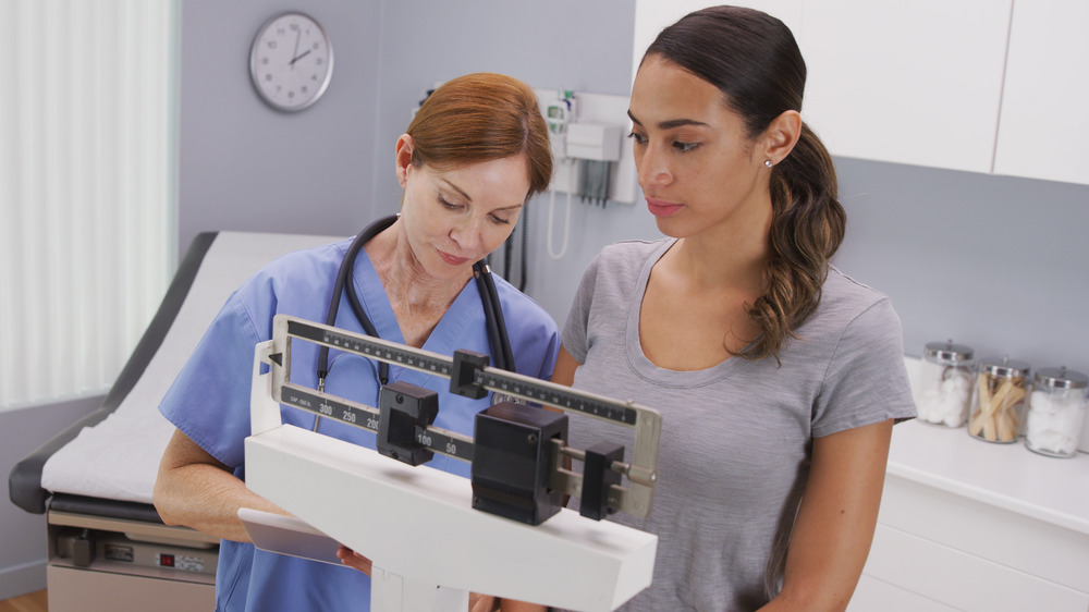 nurse recording patient's weight