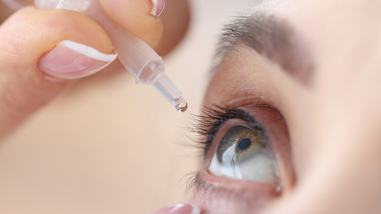 woman applying eye drops on self