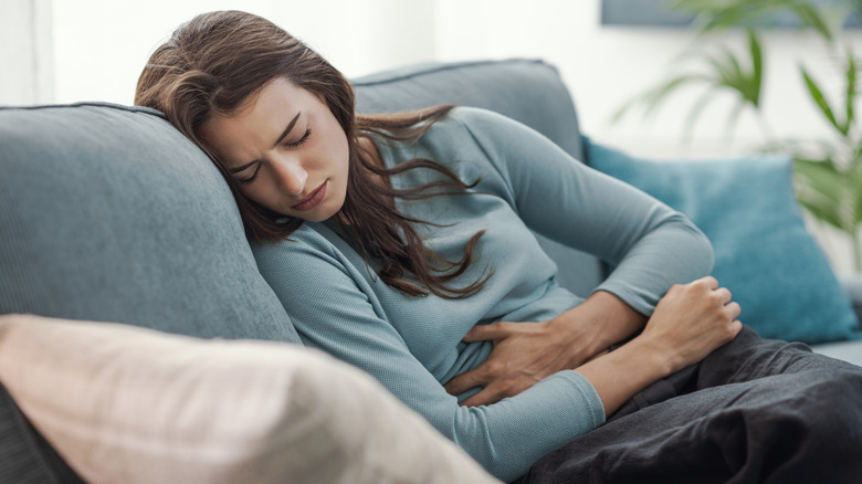 A young woman on the couch suffering from menstrual pain.