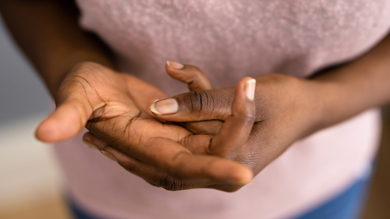 The hands of a woman cracking her fingers and knuckles.