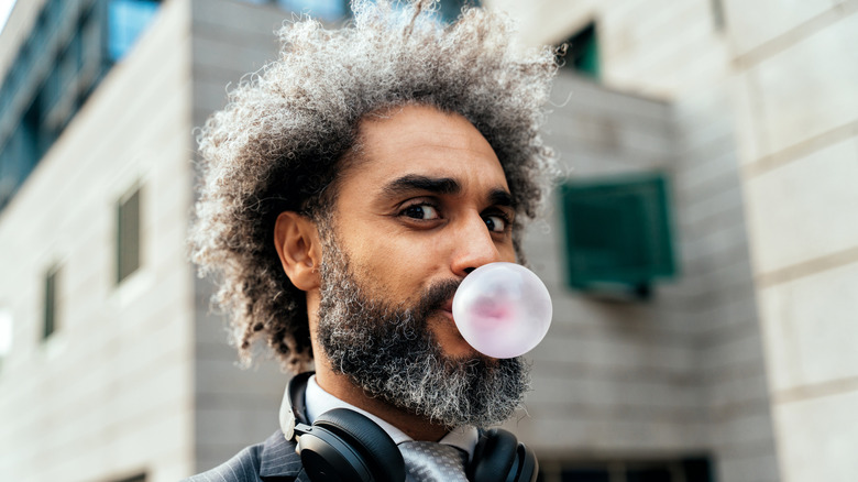 male blowing a bubble from his gum