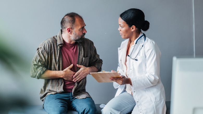 older man talking with female doctor about stomach pain