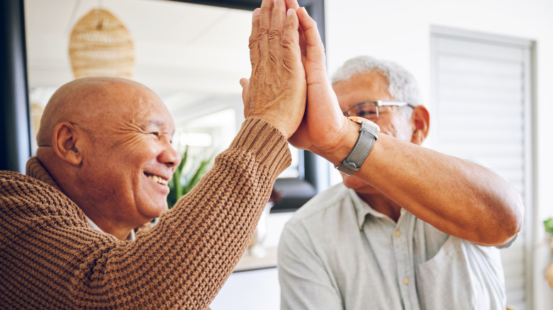 two senior men giving each other a high five