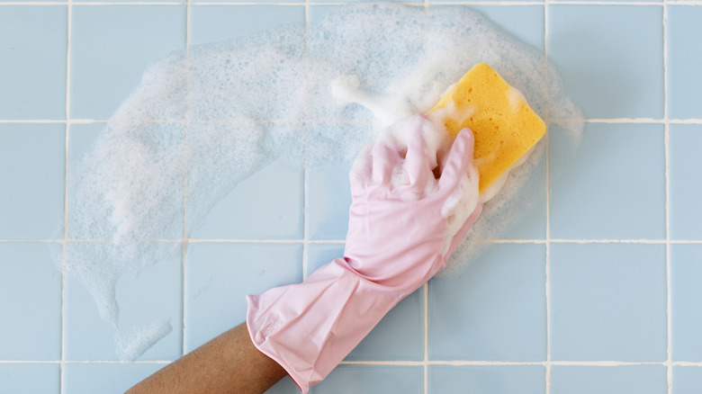 A pink-gloved hand cleaning tiles