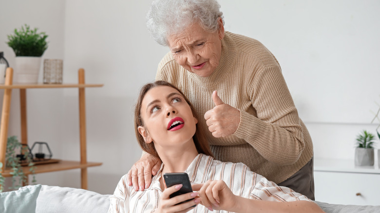 Woman giving a thumbs up while her granddaughter shows her something