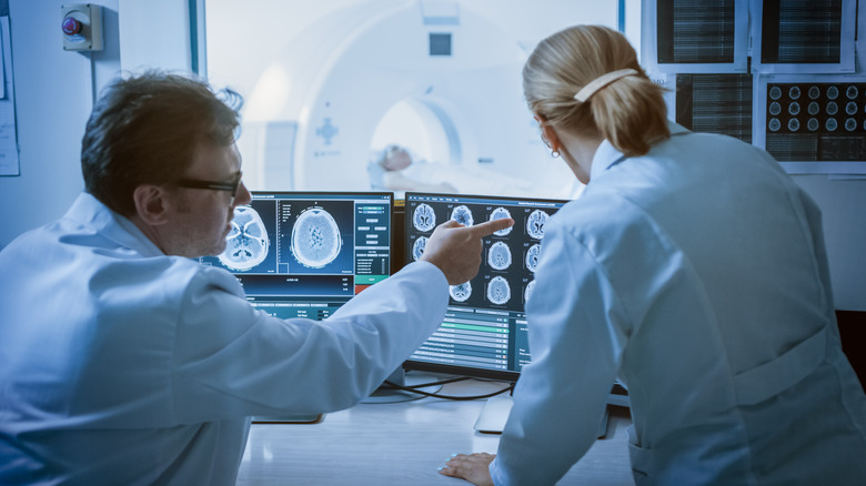 Doctor and radiologist discuss diagnosis while watching procedure and monitors showing brain scans results