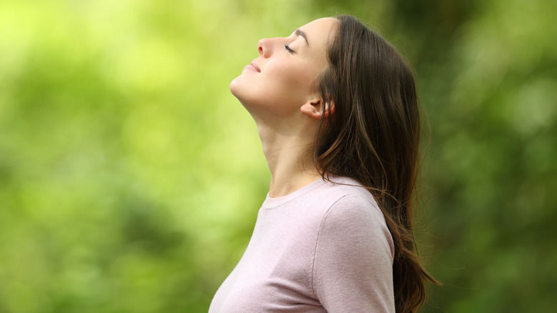 smiling woman taking deep breath outside 