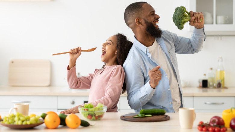 a father and daughter singing with broccoli 