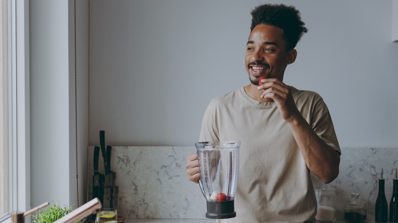 Man putting strawberries in blender