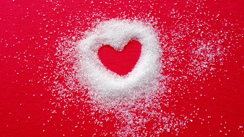 Heart shape on red cloth. Around the heart is white sugar, fading away with distance