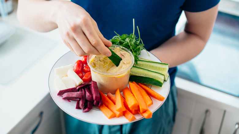 person dipping veggies in hummus