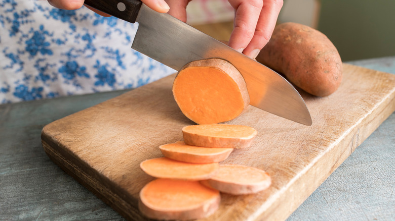 person cutting sweet potato