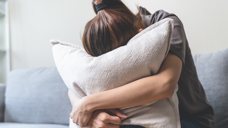 woman hiding face in pillow