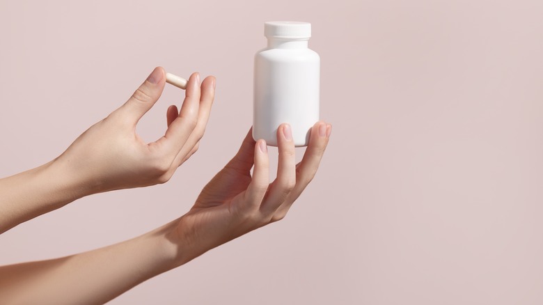 Person holding a bottle and pill