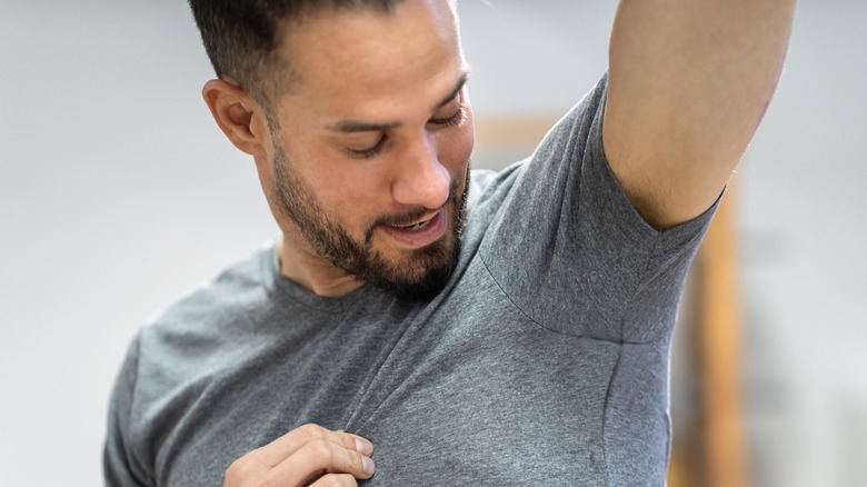 man in t-shirt checking underarm