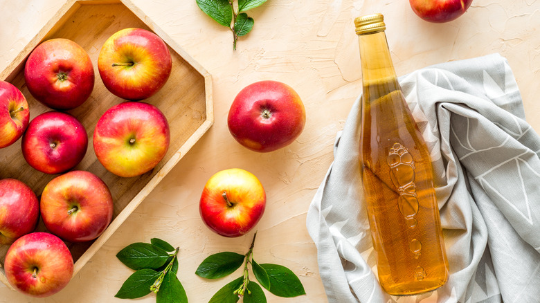 apple cider vinegar and apples on table