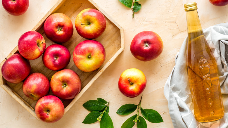 apples in box with bottle of vinegar on dish towel