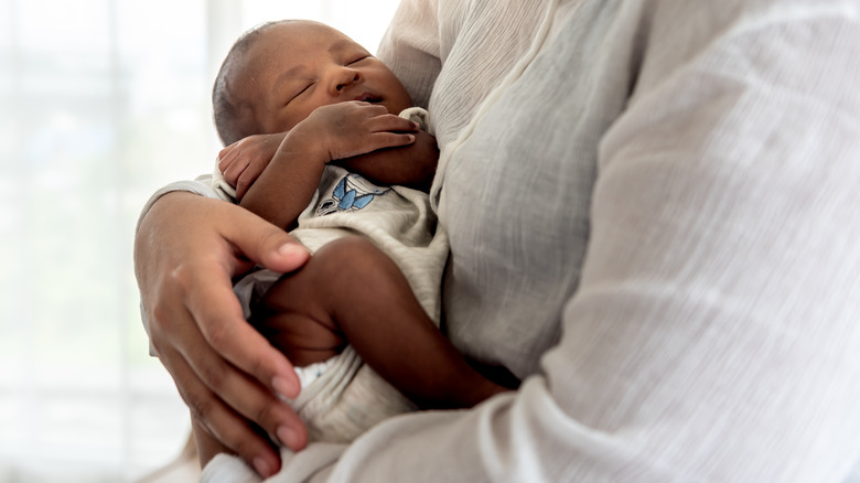 Close up on young infant held in mother's arms