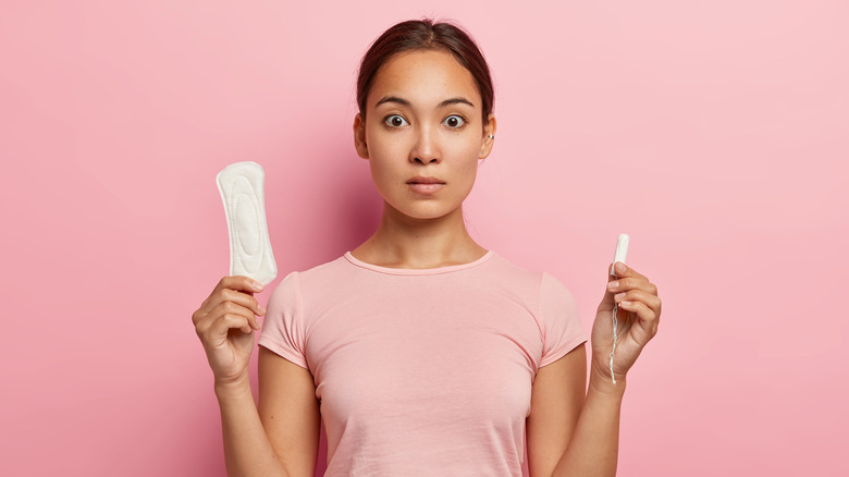 woman holding tampon and pad