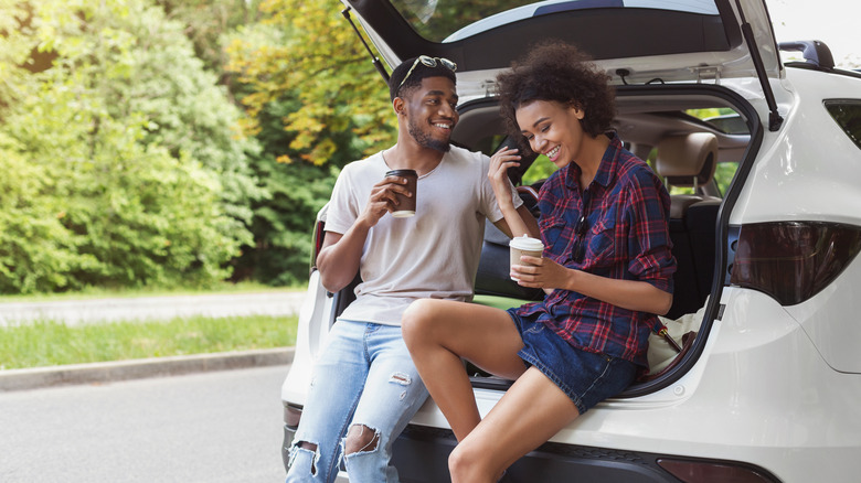 Couple sitting in car trunk parked roadside