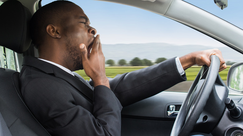 Business man driving car while yawning