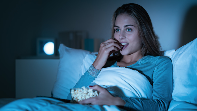 Woman eating popcorn before bedtime 