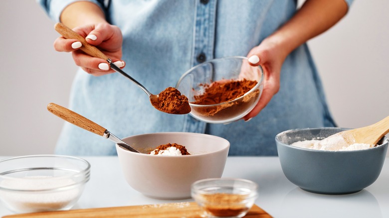 cook adding spoonfuls of cinnamon to recipe