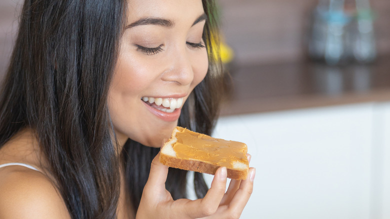 woman eating peanut butter on toast