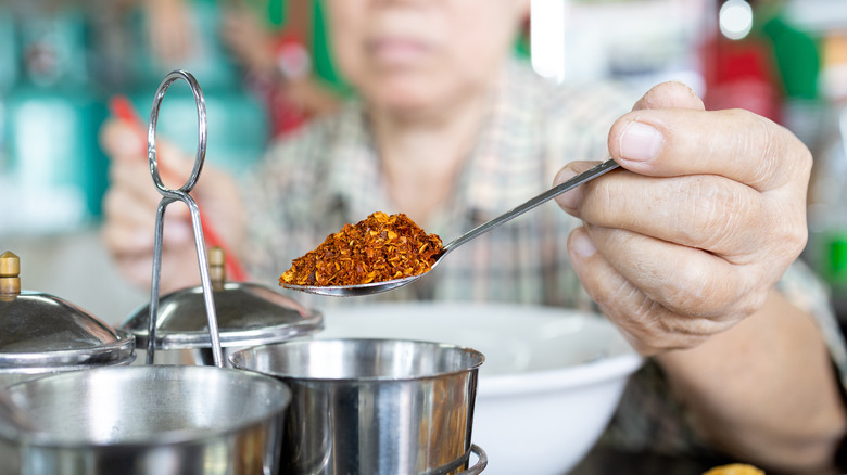 person adding spicy pepper to food