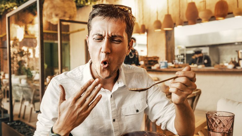 young man reacting to a spicy soup 