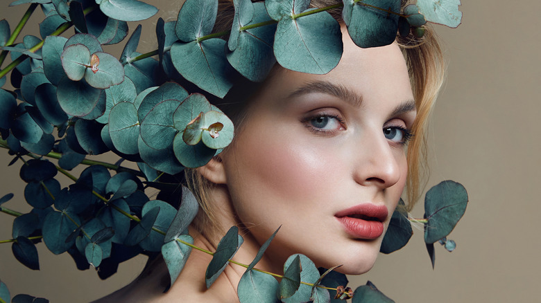 woman looking between eucalyptus branches