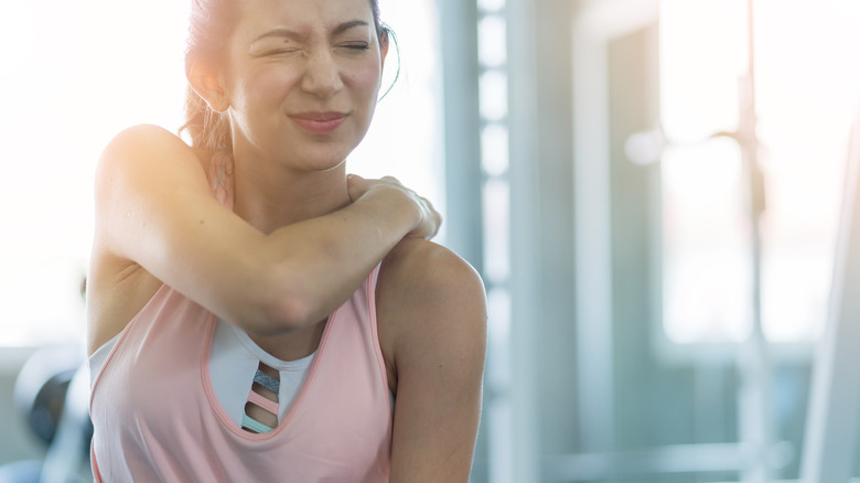Woman cringing with shoulder pain and soreness 