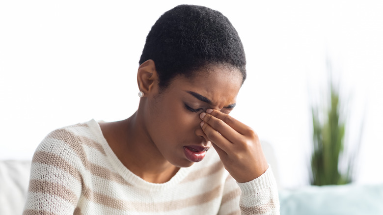 Young person holding nose in pain