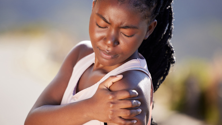 Young woman holding arm in pain