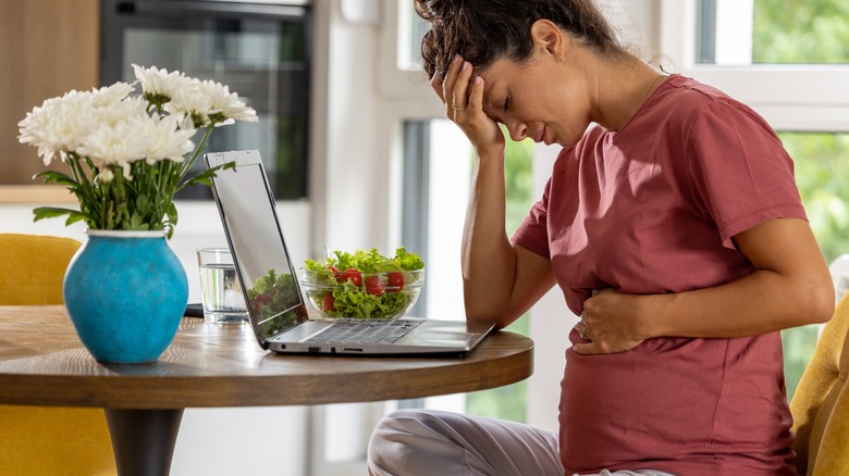 nauseous pregnant woman at laptop
