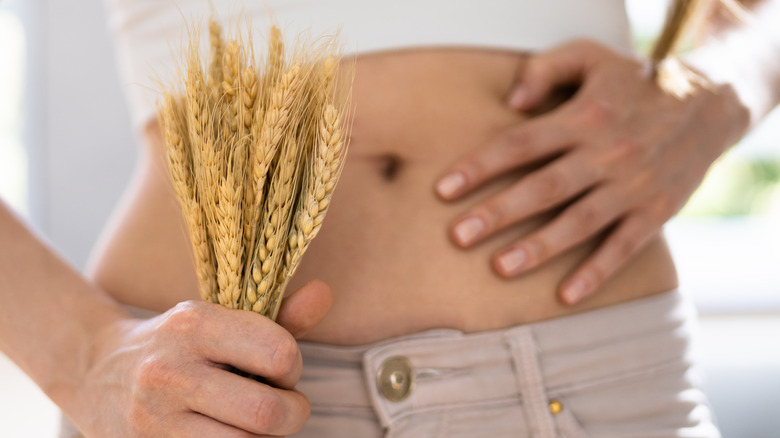 woman showing her stomach and holding grain stalks
