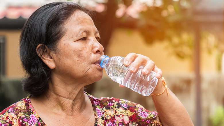 Older woman drinking water bottle