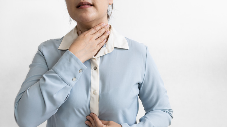 woman holding throat, touching chest