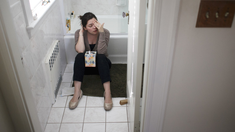woman sitting on floor of bathroom