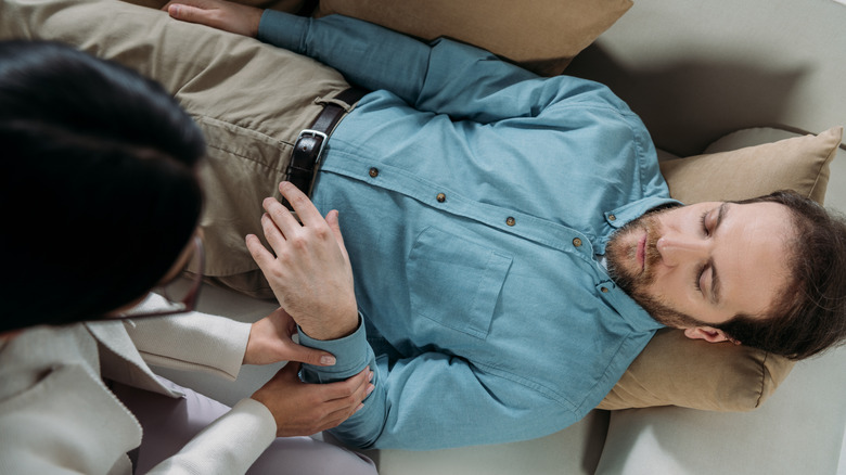 Overhead view of man lying on couch in hypnotherapy