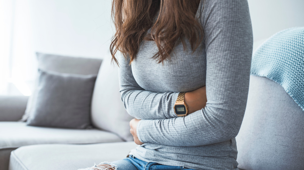 Woman holding arms over abdomen