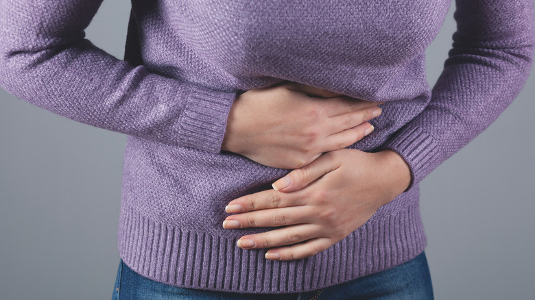 woman with hands on stomach in pain