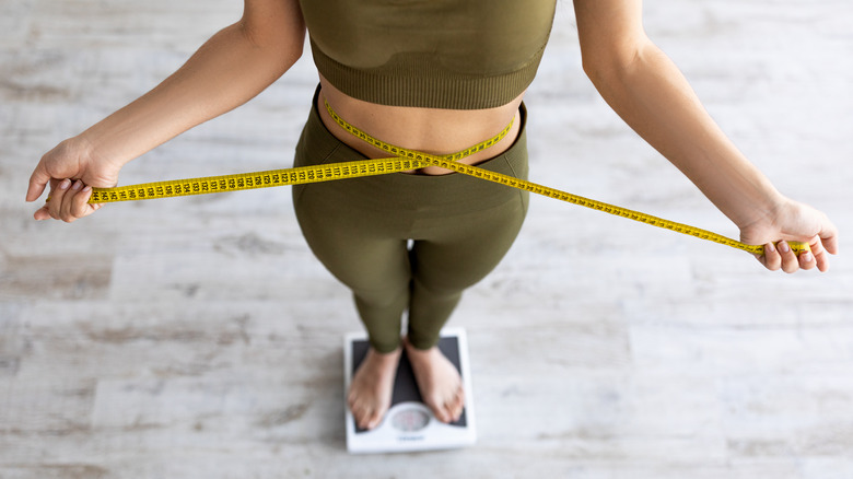 girl measuring waist on scale