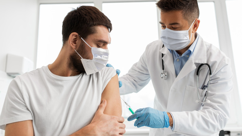A man gets a vaccine from a male doctor