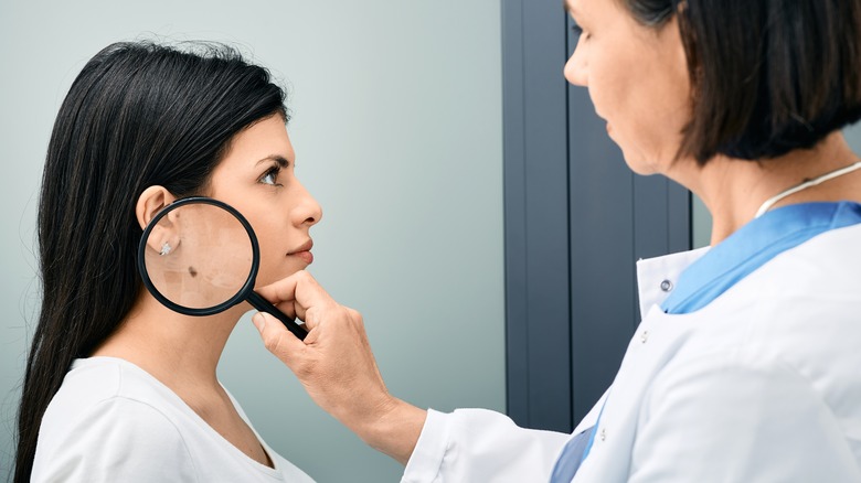 dermatologist examining patient's mole