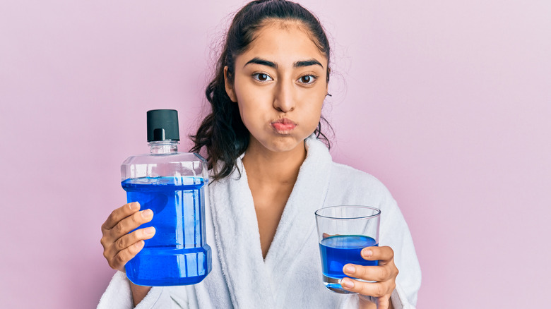 Young woman using mouthwash